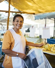 Image of a smiling woman selling bananas at a street market