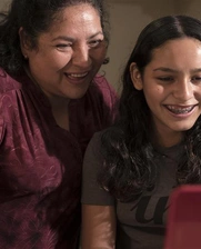 A mother and a daughter looking at a tablet and smiling 