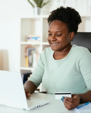 Woman looking at her compoter using  a credit card 