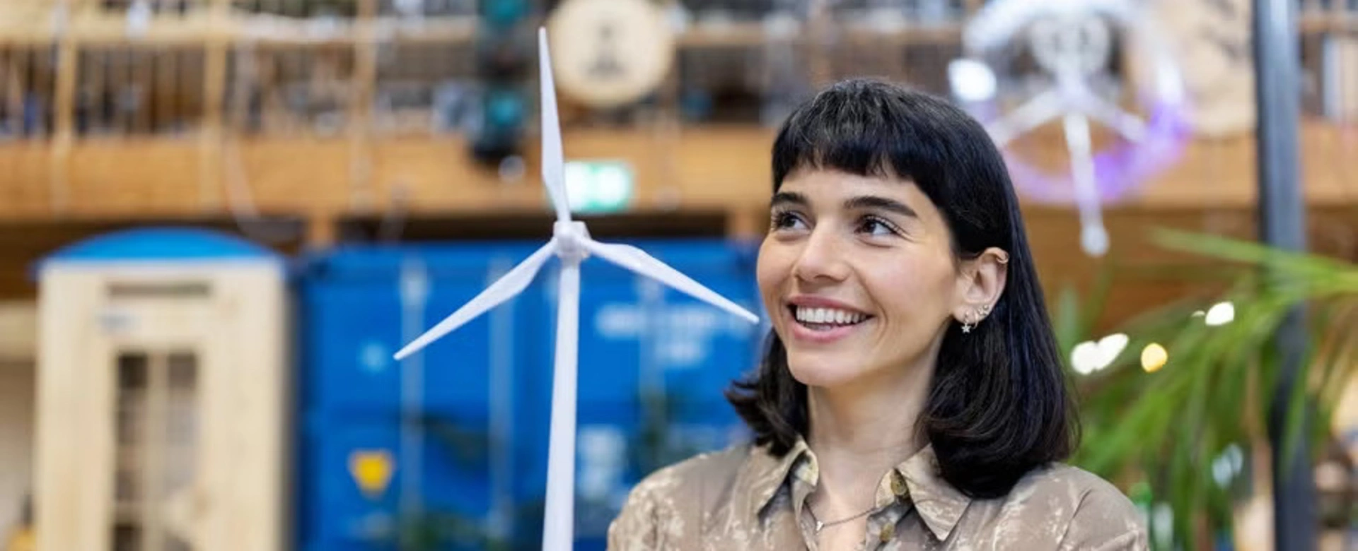 Image of a young woman smiling and holidng a wind power mill model