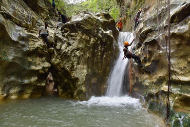 Personas haciendo escalada en una cascada.