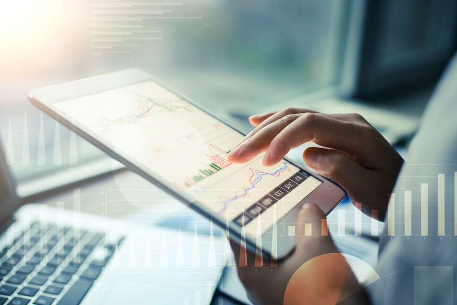 person typing on ipad with stock market
