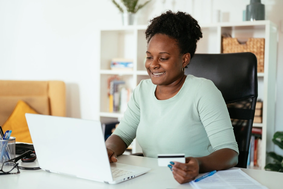 Woman looking at her compoter using  a credit card